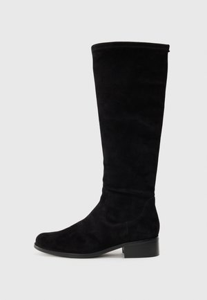 Bottes noires montantes en suède doux avec un bout arrondi et un petit talon bloc. Texture lisse avec un design sans couture et un minimum de détails.