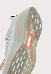 White athletic shoe sole with textured grip, orange accents, and transparent cushioning. Features a prominent "TORSION SYSTEM" label.