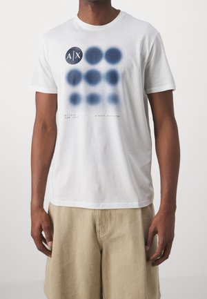 Weißes Baumwoll-T-Shirt mit einem navy-farbenen grafischen Muster aus Punkten und Branding. Klassische Passform mit Rundhalsausschnitt und kurzen Ärmeln.