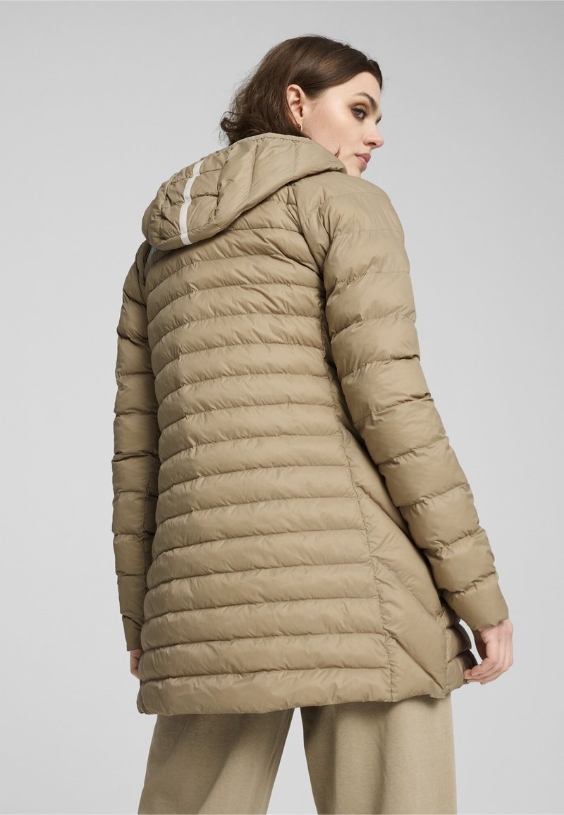 Parka acolchada beige con capucha, que presenta un acolchado horizontal, un respaldo ligeramente alargado y una franja reflectante a lo largo de la parte superior de la capucha.