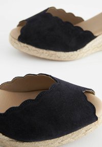 Sandalias de espadrilles de ante marino con bordes ondulados, diseño de punta abierta y suela de yute trenzada para aportar textura y soporte.