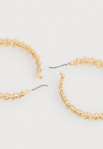 Zlaté kruhové náušnice s textúrovaným dizajnom, ktoré obsahujú malé vystupujúce guličky a priehľadné akcenty, s okrúhlym tvarom a otvoreným zadným dielom.