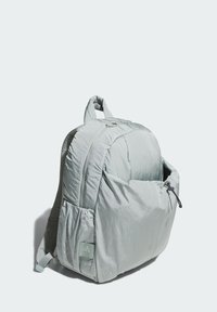 Zaino grigio chiaro con finitura testurizzata, forma arrotondata, chiusura con zip e tasca laterale. Dotato di etichetta con logo e spallacci imbottiti.