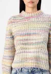 Pull en tricot multicolore avec un col haut, un tissu texturé et des rayures horizontales dans des teintes pastel de rose, vert et jaune.