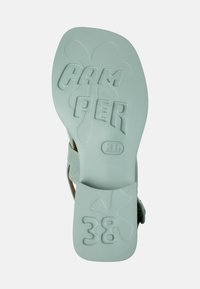 Vaaleanvihreä kuminen sandaalin pohja, jossa on kohotetut kirjaimet "CAM PER" ja koko "38", teksturoidut yksityiskohdat sekä kaareva muoto.