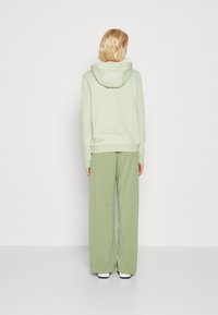 Ljusgrön hoodie med snörning i huven och matchande vida byxor i mjukt tyg, med elastiska manschetter och en avslappnad passform.