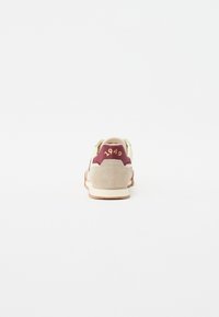 Sneaker mit einem Obermaterial aus beigem Wildleder, einem kastanienbraunen Fersenakzent und goldenen "1949"-Details. Verfügt über eine strukturierte Sohle für Grip und Unterstützung.