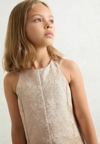 Kratka ružičasta haljina s cvjetnim uzorkom, visokim izrezom i bez rukava. Glatka tkanina s suptilnim sjajem i elegantnim detaljima uzorka.