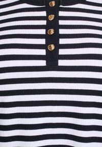 Svart och vit randig ribbad topp med rund halsringning och fem guldknappar längs placket, med en texturerad tyg.