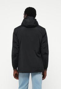 Schwarze Kapuzenjacke mit glatter Textur, lässiger Passform und langen Ärmeln. Mit elastischen Bündchen und einem Saum mit verstellbaren Elementen.