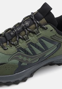 Zaļas sporta apavu ar acs un sintētiskajiem materiāliem, teksturētu virsmu, gumijas zoli ar saķeres izcilnēm un pastiprinātu šņorēšanas sistēmu.