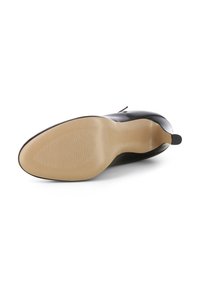 Suola di scarpe in pelle verniciata nera con una finitura liscia e un design di presa a motivo. Presenta una punta affusolata e un tacco basso.