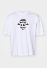 Hvid bomulds t-shirt med et grafisk print, der inkluderer "Born in New Hampshire" og "Made in New York" i sort og orange tekst.