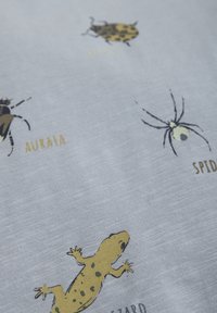 Baumwollstoff mit bunten Illustrationen von Insekten und Reptilien. Hellblauer Hintergrund mit Mustern in Gelb und Schwarz.
