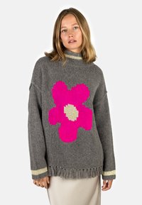 Gray knitted sweater with a large pink flower pattern, fringed hem, and striped golden accents on the sleeves. Cozy and textured design.