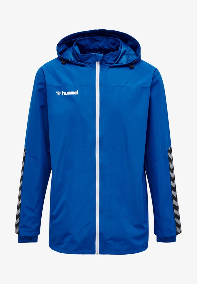 Veste imperméable bleue avec capuche, dotée d'une fermeture éclair blanche sur le devant et d'accents en chevron noir sur les manches. Logo de la marque sur le devant.