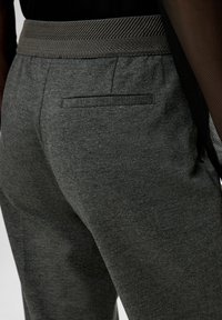 Gray trousers with a textured waistband and a back pocket. Material appears soft and stretchy, enhancing comfort and ease of movement.