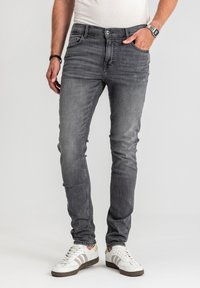 Szare jeansy z denimu o smukłym kroju, wyposażone w klasyczny wzór z pięcioma kieszeniami i subtelne wyblaknięcia. W połączeniu z białymi trampkami.