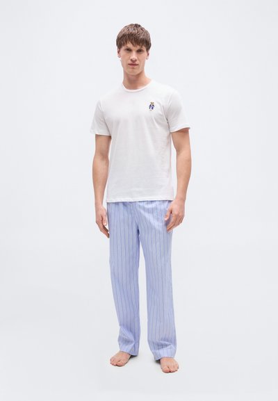 Άσπρο βαμβακερό μπλουζάκι με μικρό κεντητό σχέδιο στο στήθος, σε συνδυασμό με ανοιχτό μπλε ριγέ πυτζάμα παντελόνι, με ευθεία γραμμή.