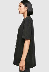 Sort oversized t-shirt lavet af bomuld, med korte ærmer og rund halsudskæring, i en afslappet pasform og et enkelt, rent design.