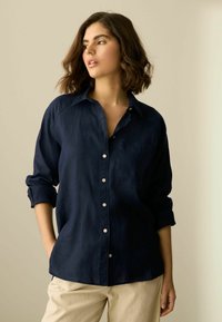 Marineblauwe, langärmige button-up blouse met een kraag, één borstzak en een relaxte pasvorm; gladde stof met een lichte glans.