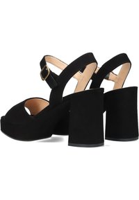 Zwarte plateau-sandalen met een chunky hak en enkelriem, voorzien van een open teen en een suède-achtige bovenkant. Gouden details.