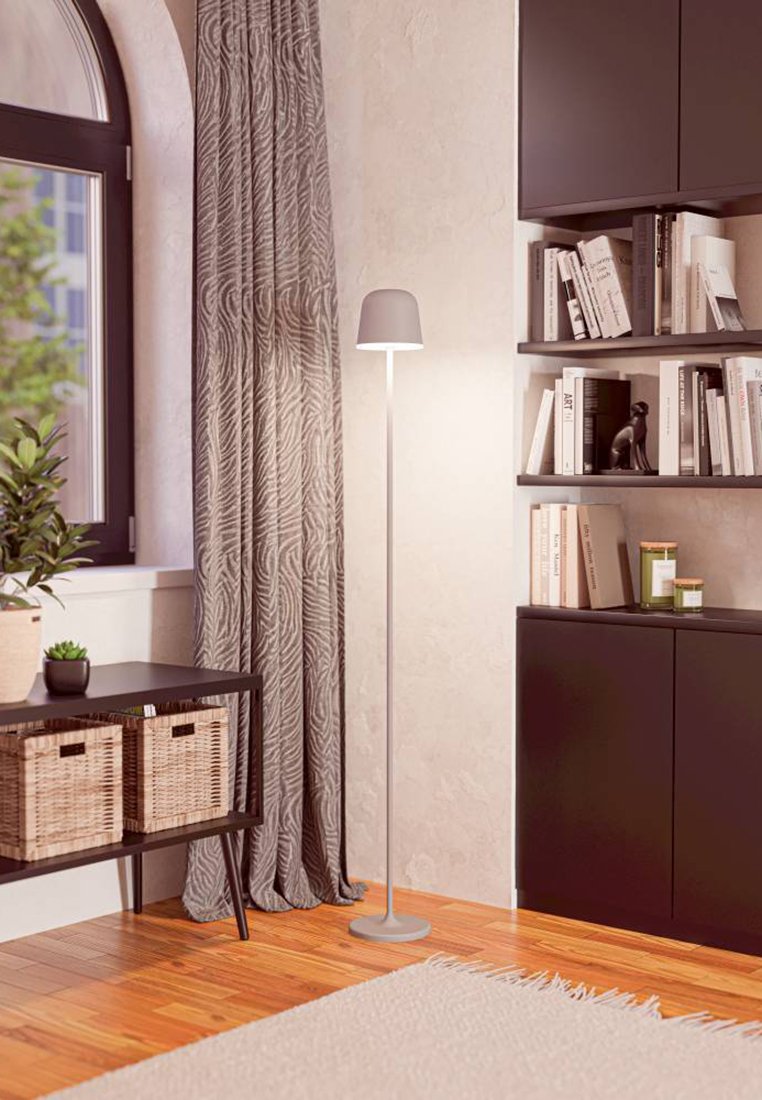 Schlanker Metallbodenlampe mit einem grauen Schirm, der auf einem runden Sockel steht. Weiche Holzböden und texturierte Vorhänge ergänzen die moderne Einrichtung.