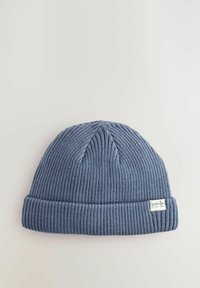 Bonnet en tricot côtelé bleu avec un revers replié. Présente une petite étiquette portant la mention "souris petit" sur le côté. Texture douce, design décontracté.