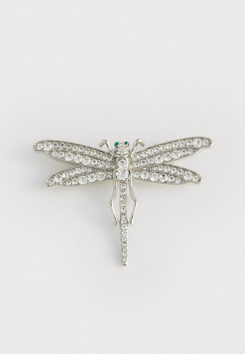 Brošňa v striebornom odtieni vo forme vážky so svetlými rhinestones a zelenými akcentovými kamienkami. Má podrobne prepracované krídla a štíhly dizajn tela.