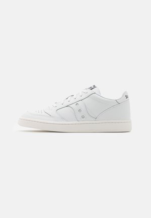 White leather sneaker with a low profile, round toe, perforated detailing, and three circular accents on the side. Rubber sole in white.