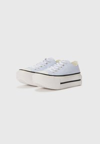 Light blue canvas sneakers with white rubber soles, black accents, and silver eyelets. Low-top design with a textured vamp and flat laces.