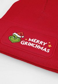 Red knit beanie featuring a patch with a green character in a Santa hat and the text "MERRY GRINCHMAS" in white, surrounded by stars.
