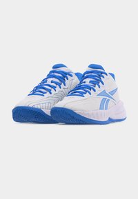 Ζεύγος λευκών και μπλε αθλητικών παπουτσιών με ύφασμα από δίχτυ, μπλε κορδόνια και σχέδια στη λαστιχένια σόλα, τοποθετημένα δίπλα-δίπλα.