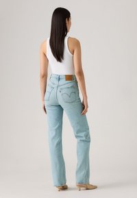 Lichtblauwe denim jeans met een hoge taille, een recht gesneden ontwerp en zichtbare achterzakken. Bevat een bruine leren merkembleem op de taille.