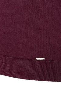 Burgunderfarbener, gestrickter Pullover mit rippenförmigem Saum. Verfügt über ein kleines silbernes Etikett mit "MORE & MORE" nahe dem unteren Rand. Weiche Textur und taillierte Passform.