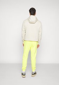 Nike Sportswear CLUB JGGR - Tracksuit bottoms - yellow strike