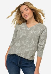 Szary długi rękaw koszulka z dekoltem w serek, z białymi wzorami żaglówek na teksturowanym tle. W połączeniu z niebieskimi dżinsami.