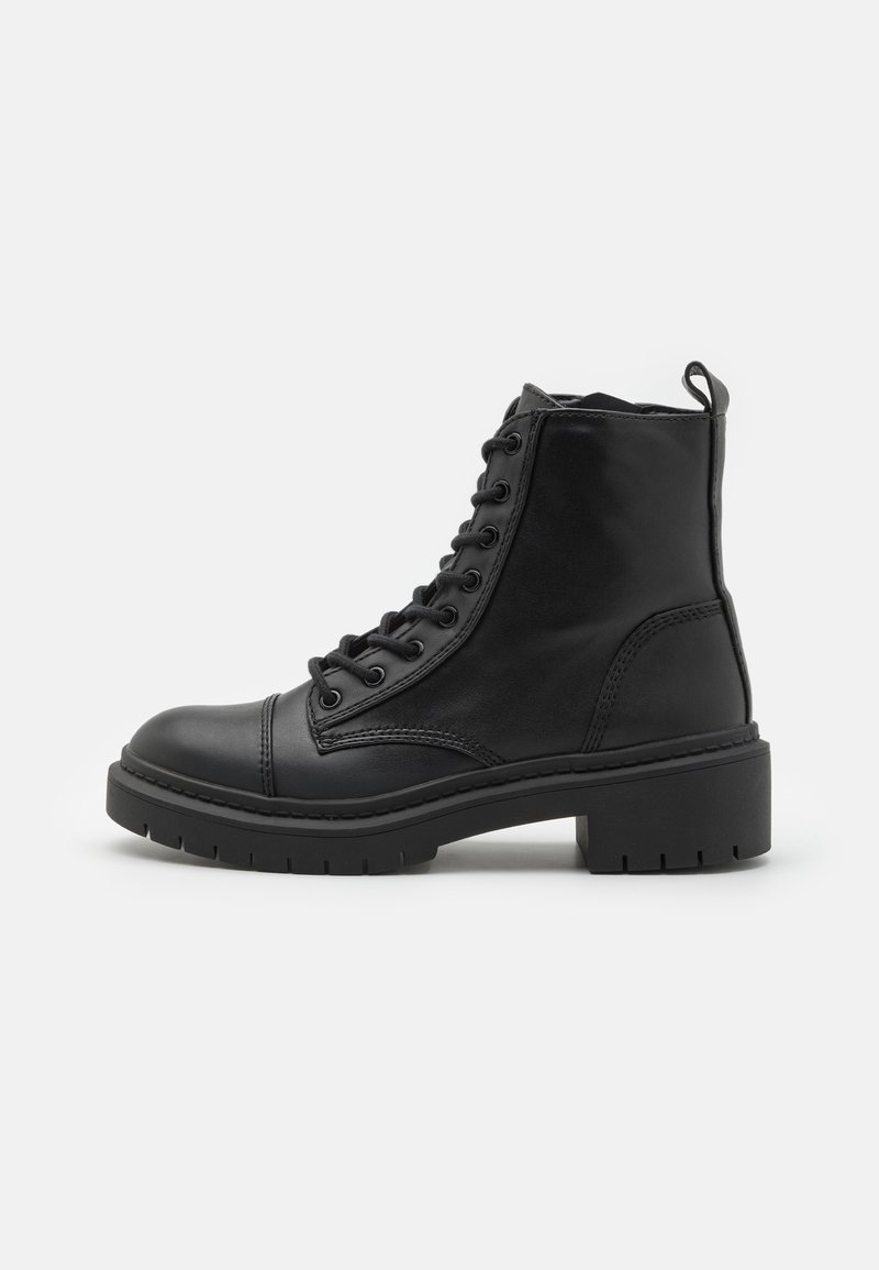Bottine en cuir noir à bout rond, à lacets à l'avant, avec une semelle en caoutchouc épaisse et un petit talon. Présente des détails de couture et une languette.