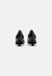 Black patent leather high heels with a pointed toe and a short block heel, featuring a smooth and glossy surface.