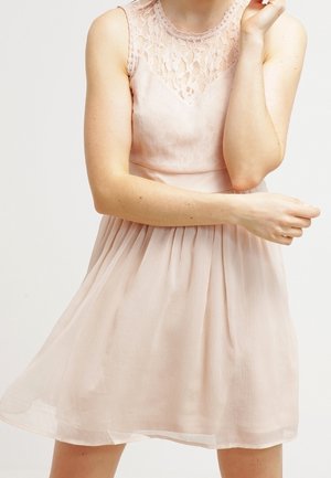 Robe rose clair avec corsage en dentelle et jupe plissée, confectionnée en tissu transparent. Comprend un col rond et un design sans manches.