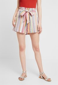 Pantaloni corti di lino a strisce nei colori pastello con vita a sacchetto, cintura in raso e vestibilità rilassata, abbinati a sandaletti piatti argentati.