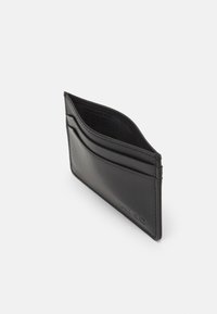 Black leather card holder featuring multiple card slots, a smooth texture, and embossed logo detailing on the front. Slim and minimalist design.