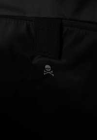 La tela negra presenta un pequeño diseño de calavera y huesos cruzados en gris claro. Tiene una correa duradera con un acabado texturizado.