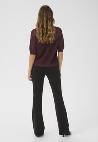 Burgundy knit sweater with short sleeves and a loose design, paired with black flared trousers and heels for a streamlined silhouette.
