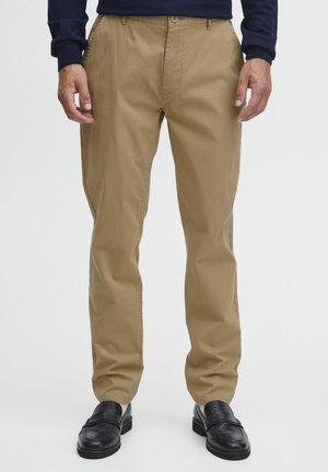 Khaki chinos with a straight leg design, made of smooth fabric, featuring a button closure and front pockets. Worn with black loafers.