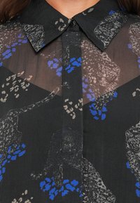 Camicia nera realizzata in un tessuto trasparente con motivi leopardati grigi e accenti floreali blu. Presenta un colletto classico e chiusura con bottoni.