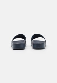 Marina slide-sandaler med ett mjukt material, öppen bak, dubbla kurviga remmar och en texturerad sula för komfort.