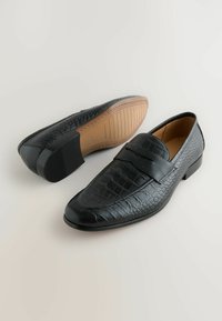 Schwarze Lederloafers mit einem Krokodil-Muster, abgerundeter Zehe und einem dekorativen Band. Verfügt über einen niedrigen Absatz und eine strukturierte Gummisohle.