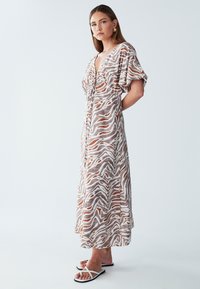 Maxikleidi kergest kangast, pruunide ja valgete sebratriipudega, lendlevate varrukatega ja sügava V-kaelusega.