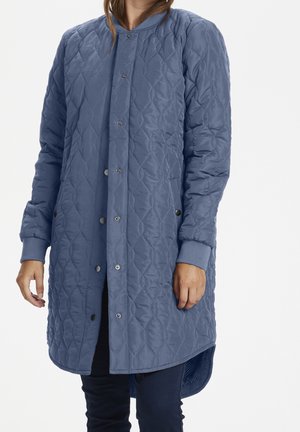 Vadderad lång kappa i mjukt blått tyg, med knappstängning, ribbade ärmar och en rundad nederkant med en lätt svans.